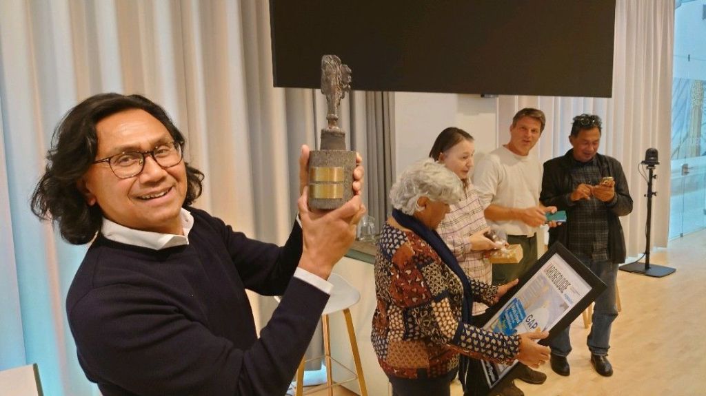 Wijlfries Saeboe houdt het beeldje van de Grote Archeologie Prijs omhoog, terwijl Shima Pattisuhasiwa de oorkonde bekijkt. (Foto Jobbe Wijnen)